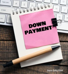 Notepad with pink sticky note reading "Down Payment" next to pen and keyboard – concept image for mortgage and home buying costs